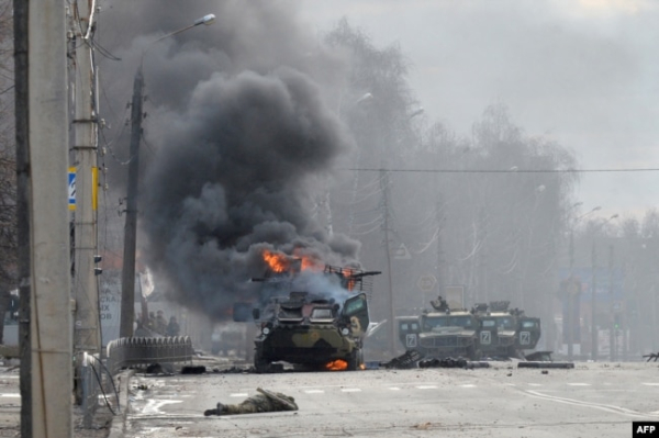 Російський БТР горить поруч із тілом військового після боїв у Харкові, 27 лютого 2022 року