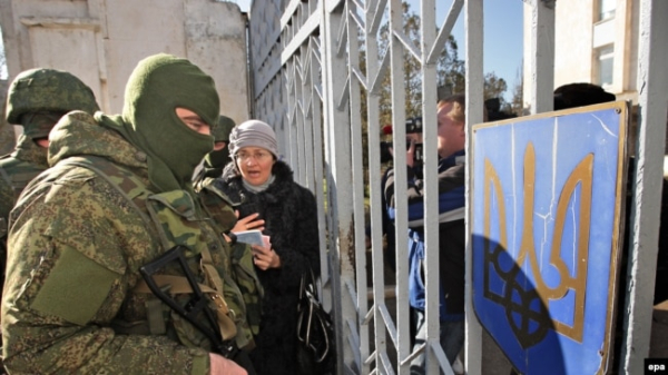 Українські жінки розмовляють із чоловіками, одягненими в російську військову форму, які блокують українських військових у Новоозерному неподалік Євпаторії, 3 березня 2014 року