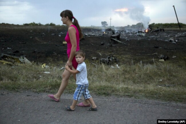 Жінка з дитиною проходить повз одне з місць падіння уламків «Боїнга», збитого російською установкою «Бук», 2014 рік