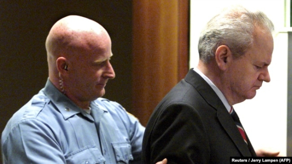 Колишнього президента Югославії Слободана Мілошевича (праворуч) ведуть до зали суду Трибуналу ООН, липень 2001 року