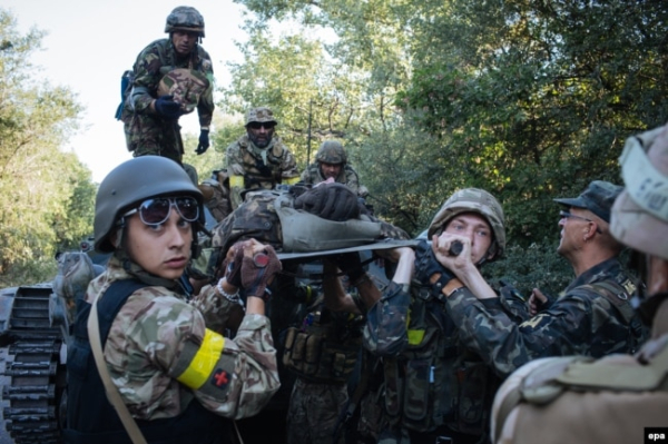Українські військові несуть пораненого під час бою проти російсько-гібридних сил поблизу міста Іловайська, 10 серпня 2014 року