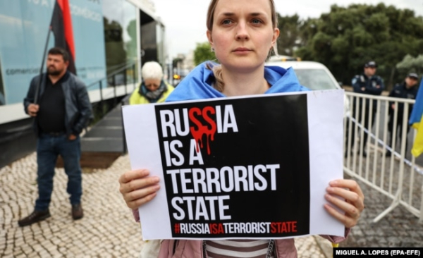 Жінка з плакатом «Росія – терористична держава» перед посольством Бразилії в Португалії на акції протесту проти висловлювань бразильського президента Луїса Інасіо Лули да Сілви щодо війни Росії проти України. Лісабон, 21 квітня 2023 року