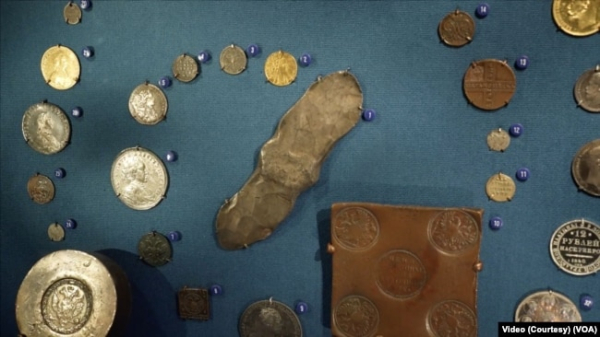 Українська срібна гривня (в центрі) посеред колекції російських грошей