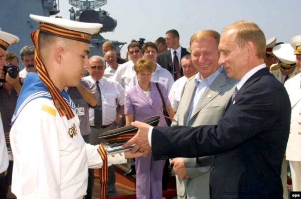 Президент России Владимир Путин (справа) получает матросскую бескозырку от моряка Черноморского флота России, рядом с ним находится президент Украины Леонид Кучма. Севастополь, 29 июля 2001 года