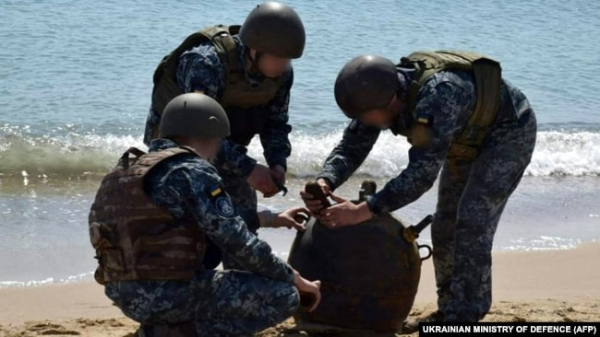 Українські військові знешкоджують морську міну, викинуту на берег штормом, під час масштабного вторгнення Росії в Україну, 2022 рік