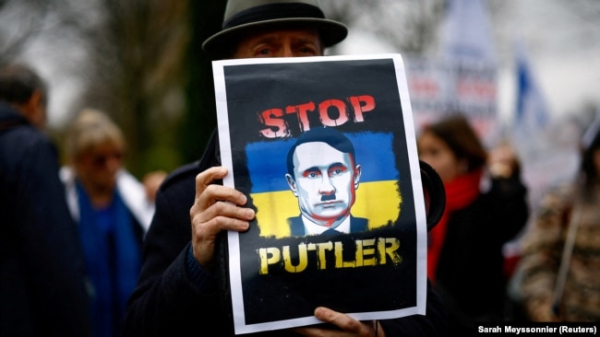 Чоловік на акції протесту із зображенням Володимира Путіна у вигляді Адольфа Гітлера біля посольства Росії у Франції. Париж, 17 березня 2024 року 