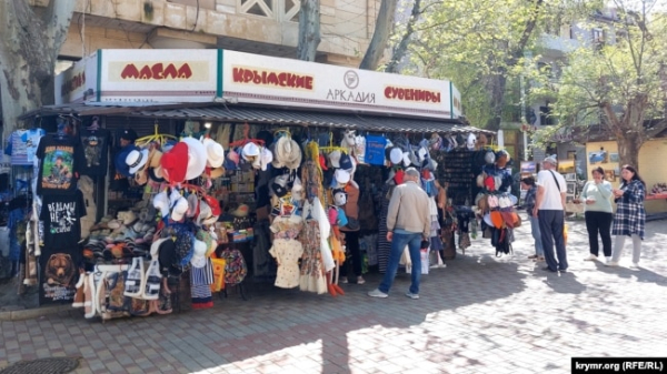 Люди біля сувенірної крамниці в центрі Феодосії напередодні початку курортного сезону, 15 квітня 2024 року